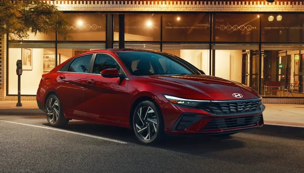Modern sedan driving smoothly on an open two-lane paved highway in a mountain valley setting