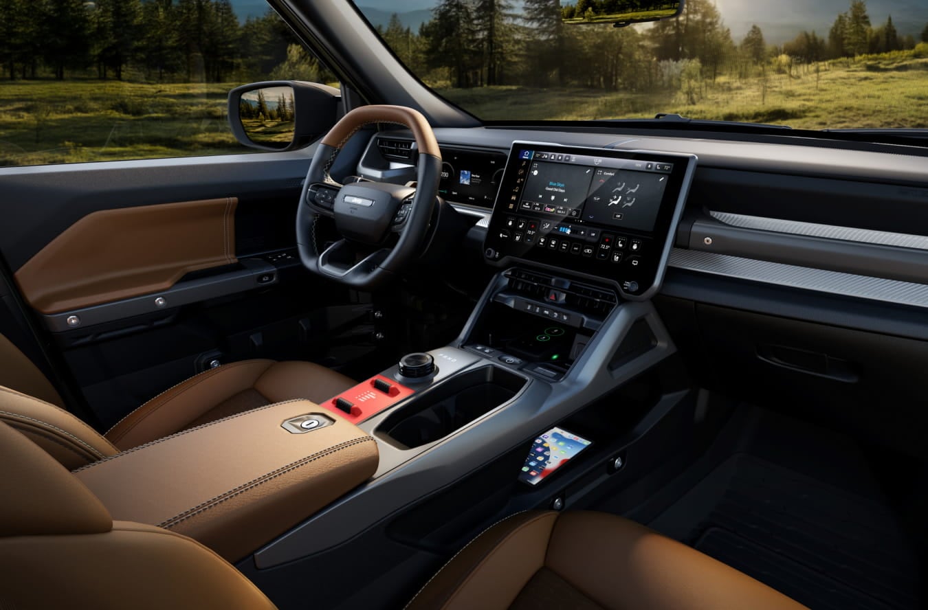2026 Jeep Recon interior featuring leather seats, a sleek dashboard with a large touchscreen, and a scenic forest view through the windows.