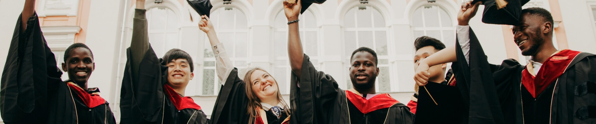 Group of graduates lifting up their graduation caps