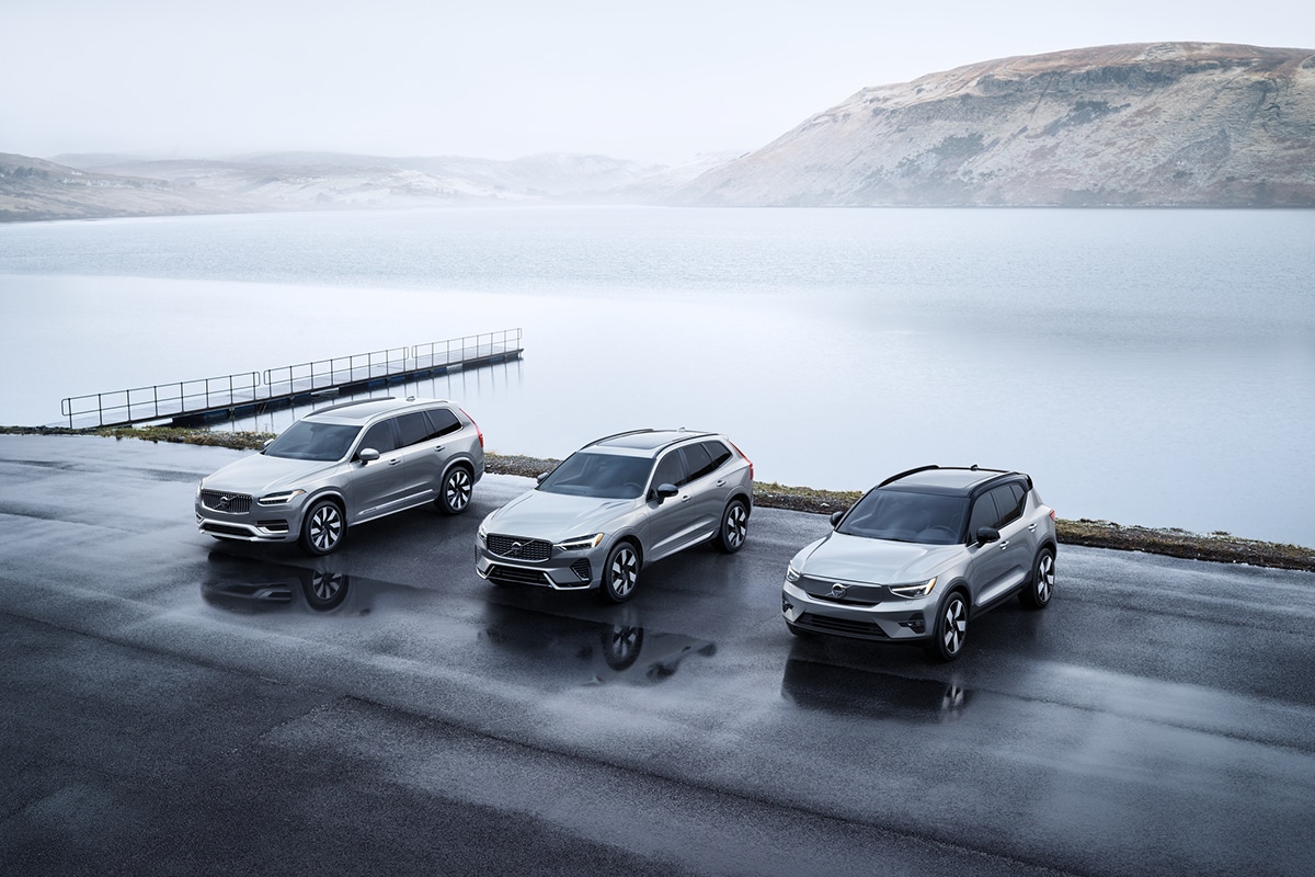 In-Transit Volvo Models A Volvo XC40 Recharge Pure Electric, XC60 Recharge Plug-In Hybrid, and XC90 Recharge Plug-In Hybrid parked near a lake's edge