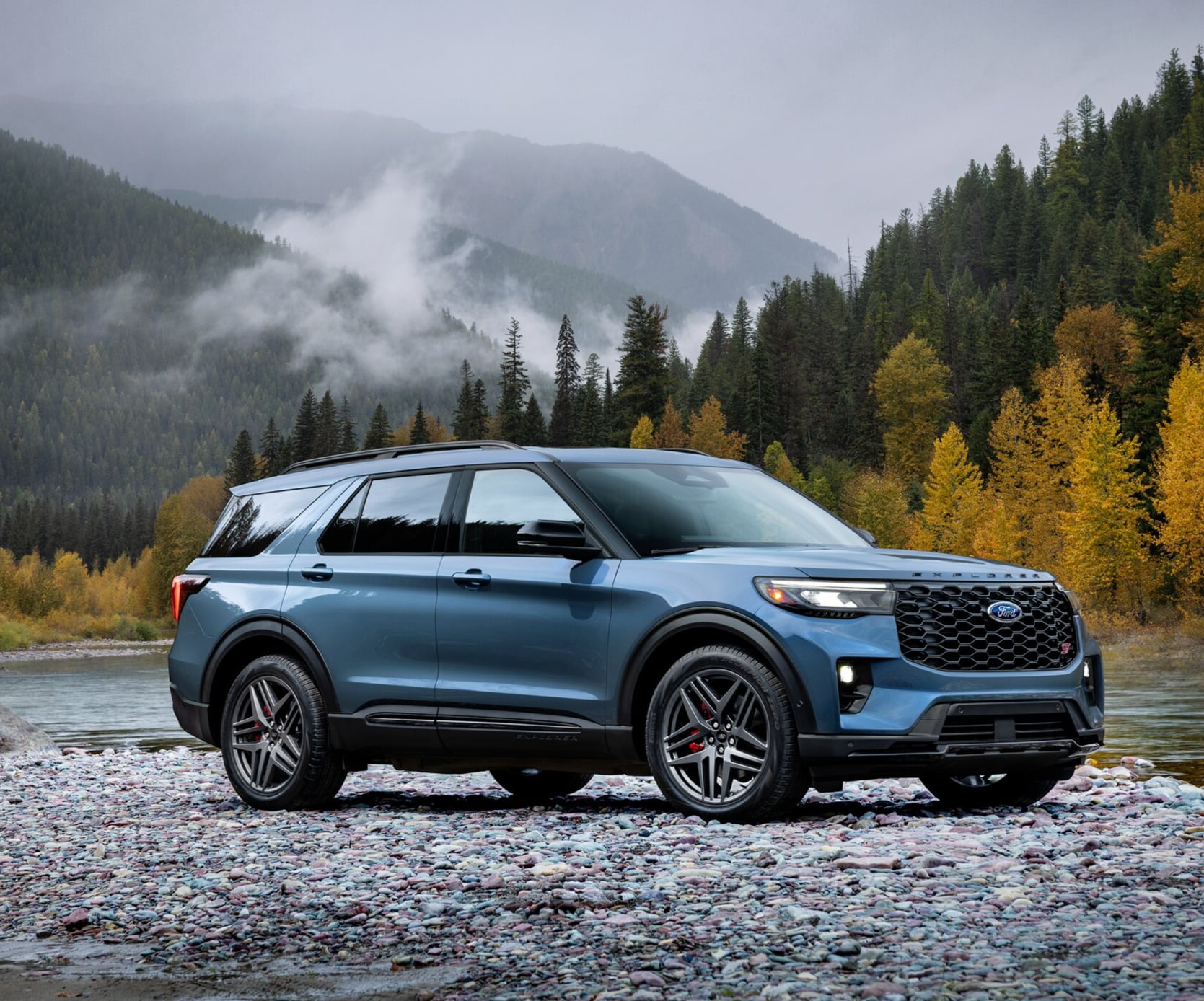 Ford Explorer parked by river with scenic mountain background