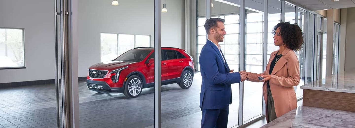 Women taking the keys of a cadillac from a salesman