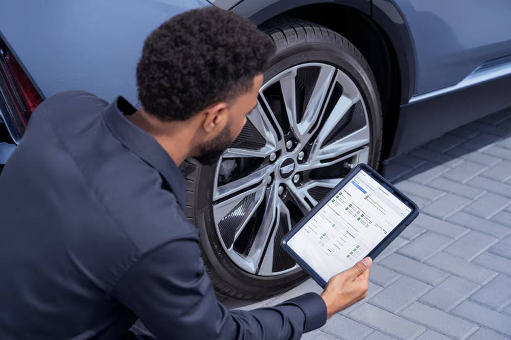 Cadillac Mechanic with a checklist next to a tire