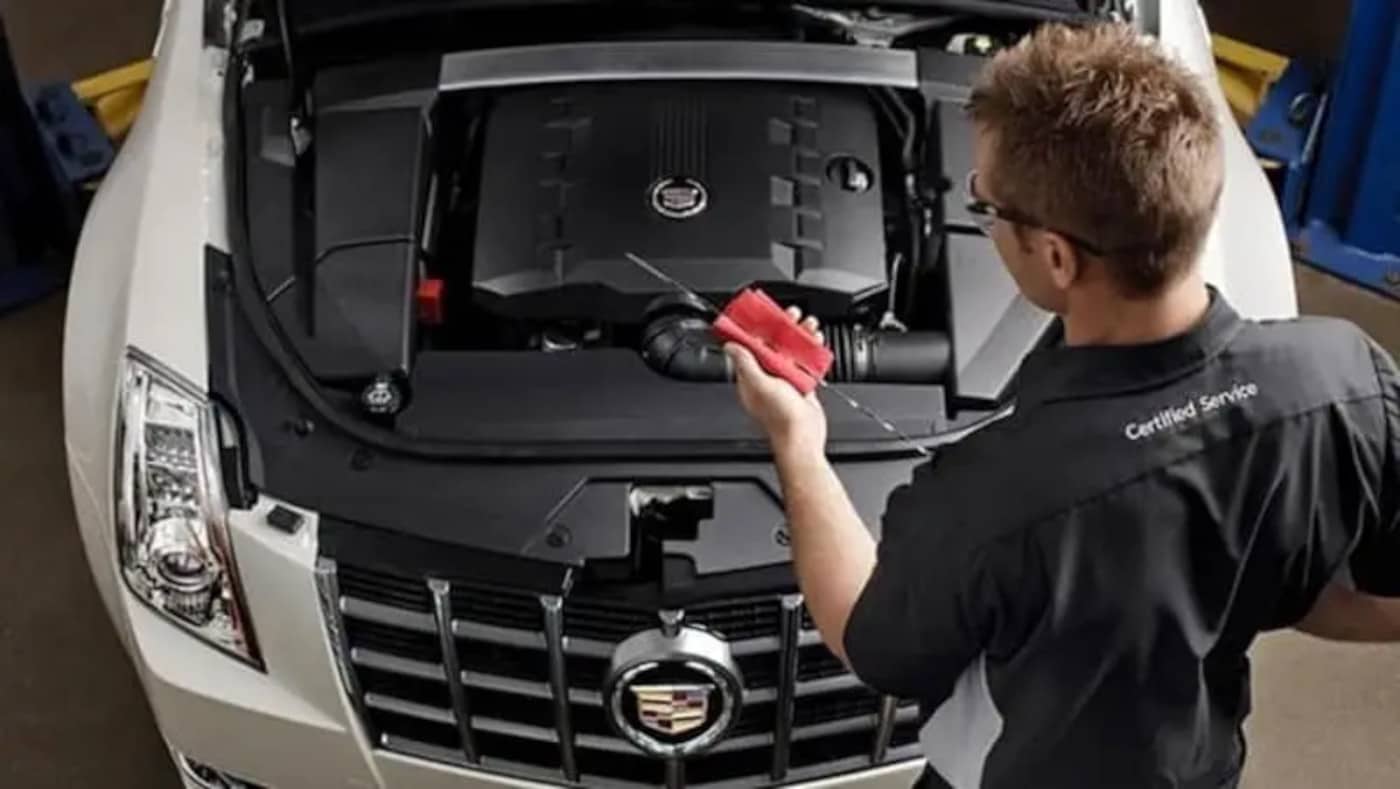 Cadillac mechanic checking the oil dipstick