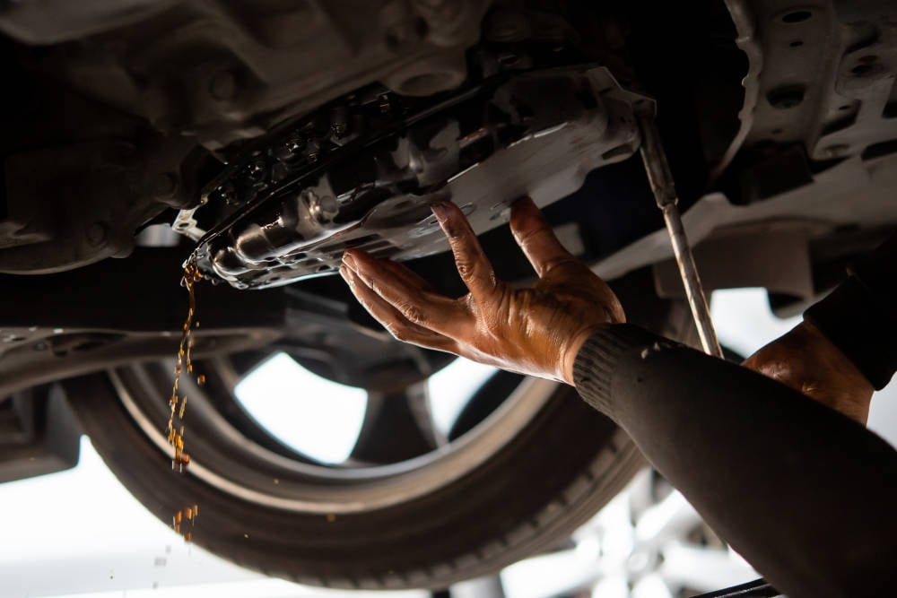 Cadillac mechanic servicing transmission fluid