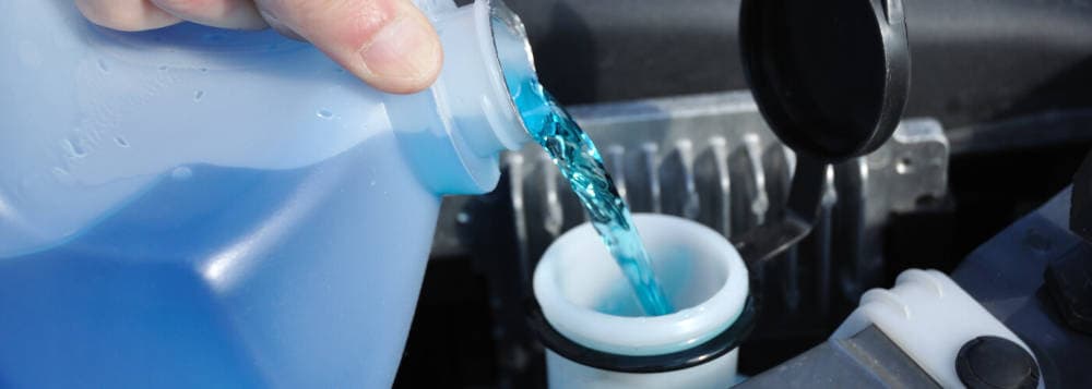 Pouring fluid into the windshield wiper fluid reservoir