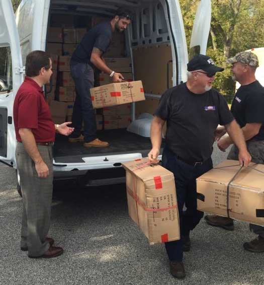 Dom Conicelli Jr. and employees unload and deliver new winter coats to needy students.