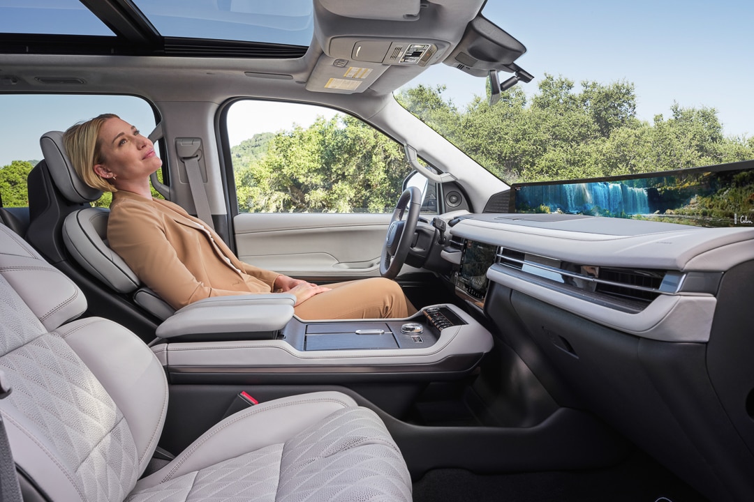 Woman with blonde hair reclines in the driver seat of a 2025 Lincoln Navigator as she experiences Lincoln Rejuvenate in-car spa feature.