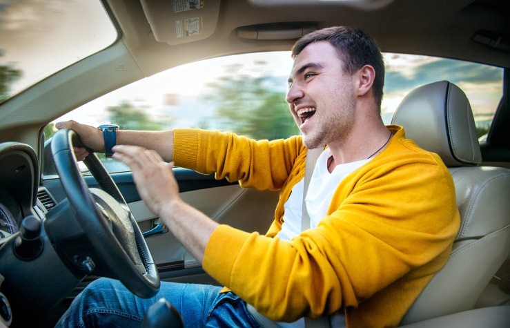 Male teenager driving off in their new car
