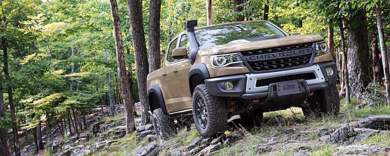 A 2023 Chevy Colorado driving off road through the forest.