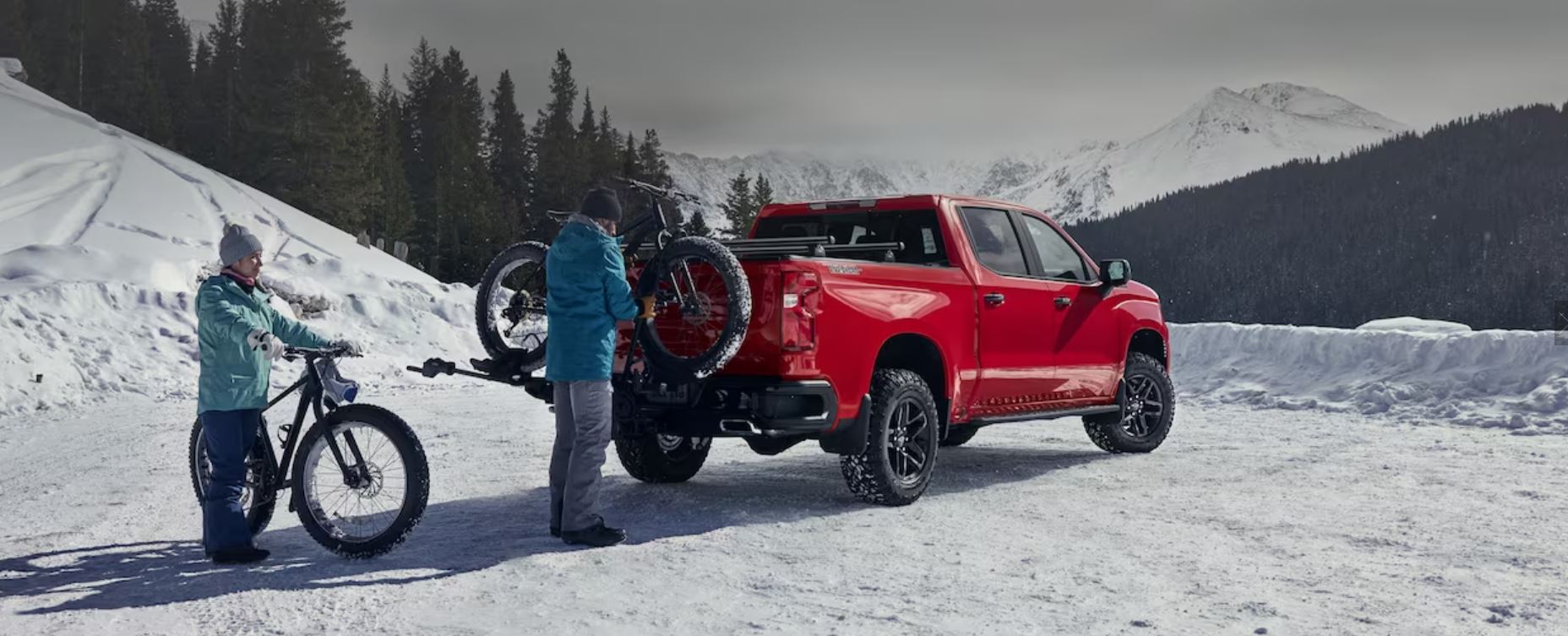 A couple taking their Chevy truck to a snow covered trailhead to ride bikes with fat winter tires.
