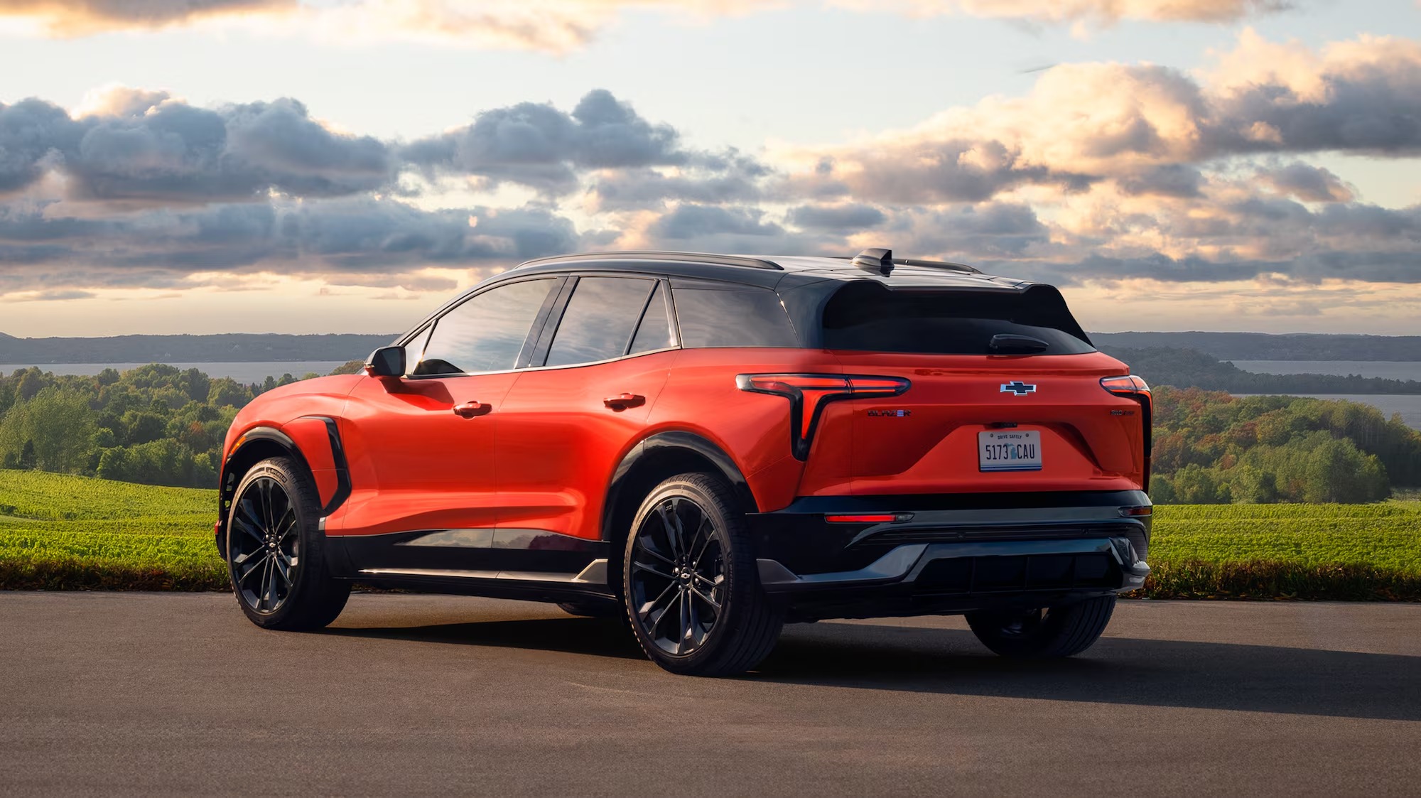 Red 2026 Chevy Blazer EV, rear three-quarter view, parked on an overlook at sunset