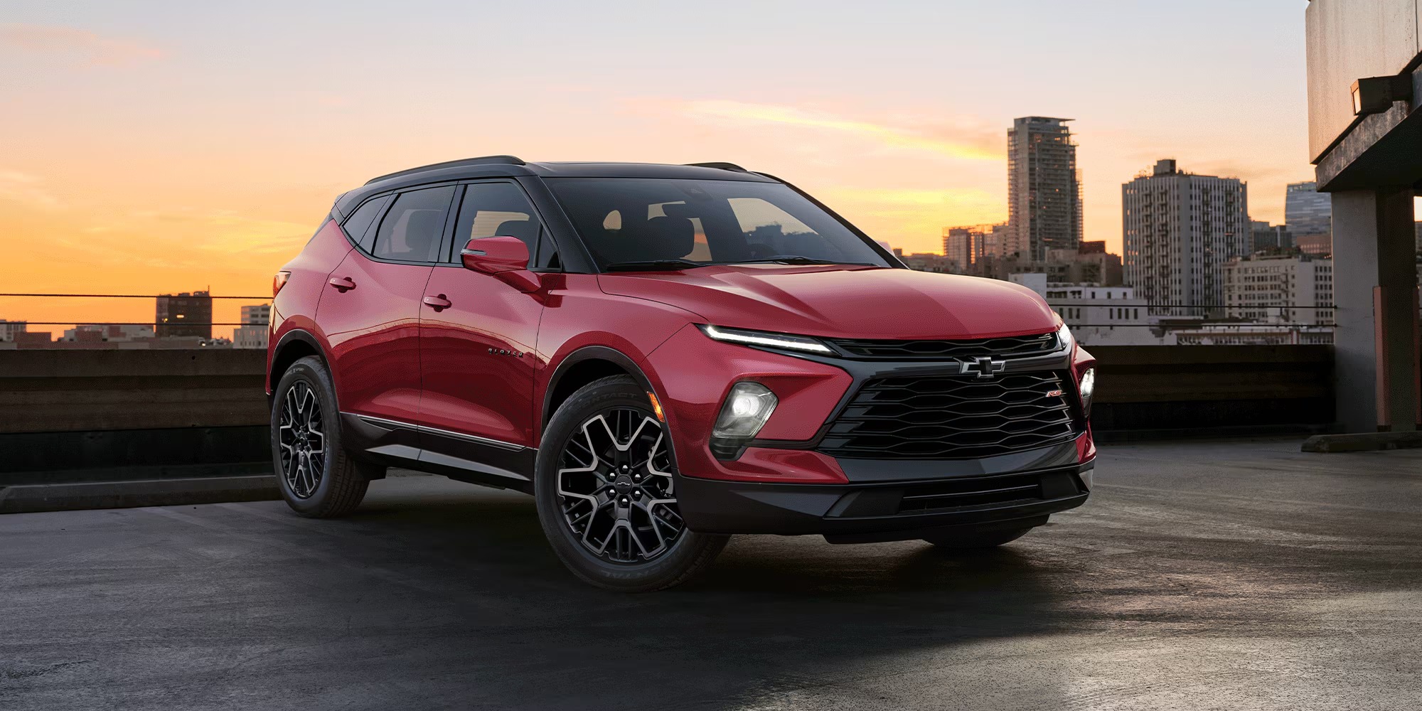 Red 2026 Chevy Blazer RS parked on a rooftop with a city skyline at sunset