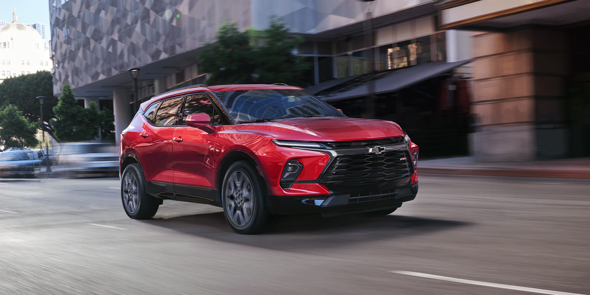 Red 2026 Chevy Blazer driving on a downtown city street