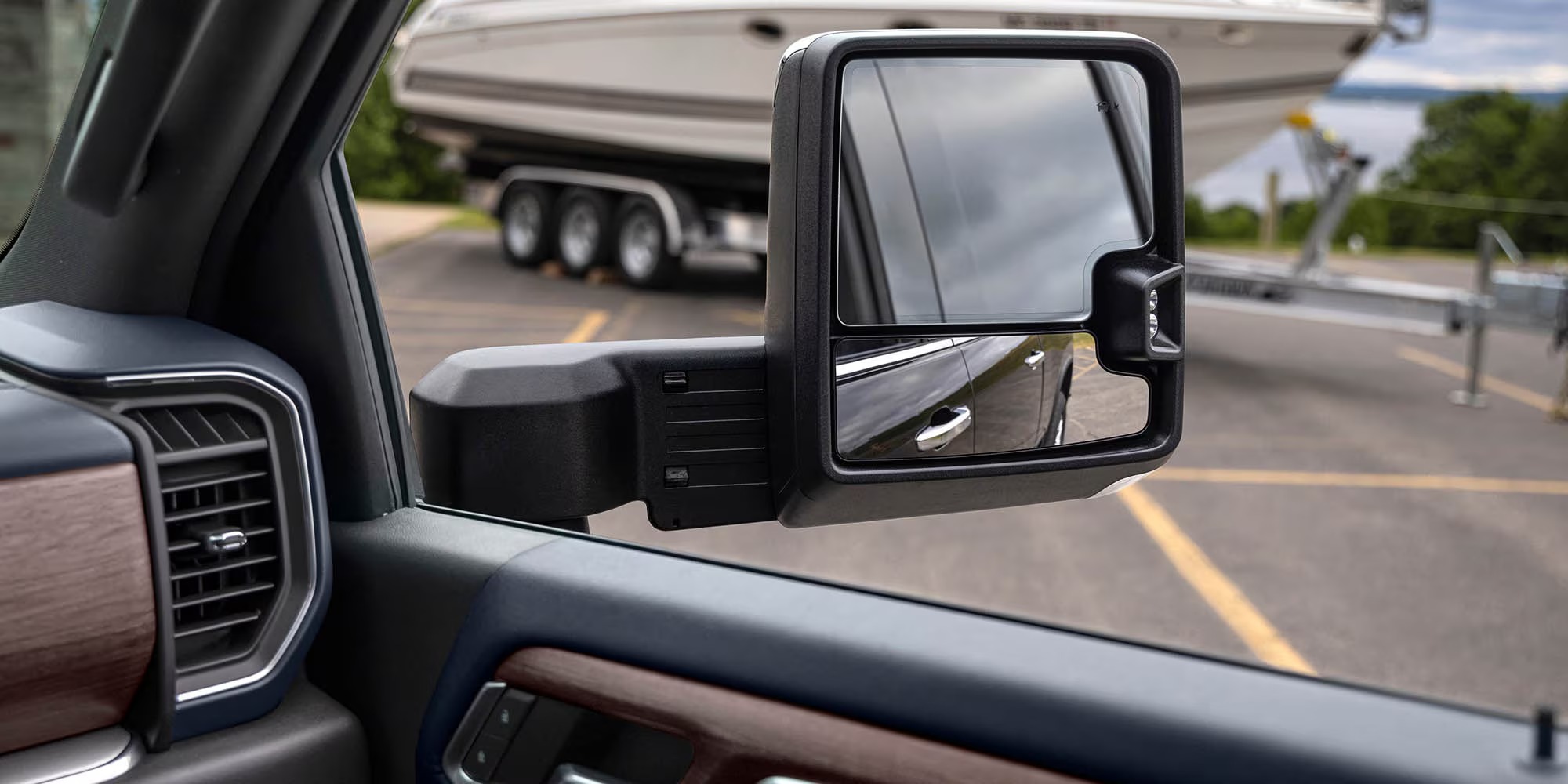 View through a Chevy Silverado HD extended towing mirror of a boat on a triple-axle trailer
