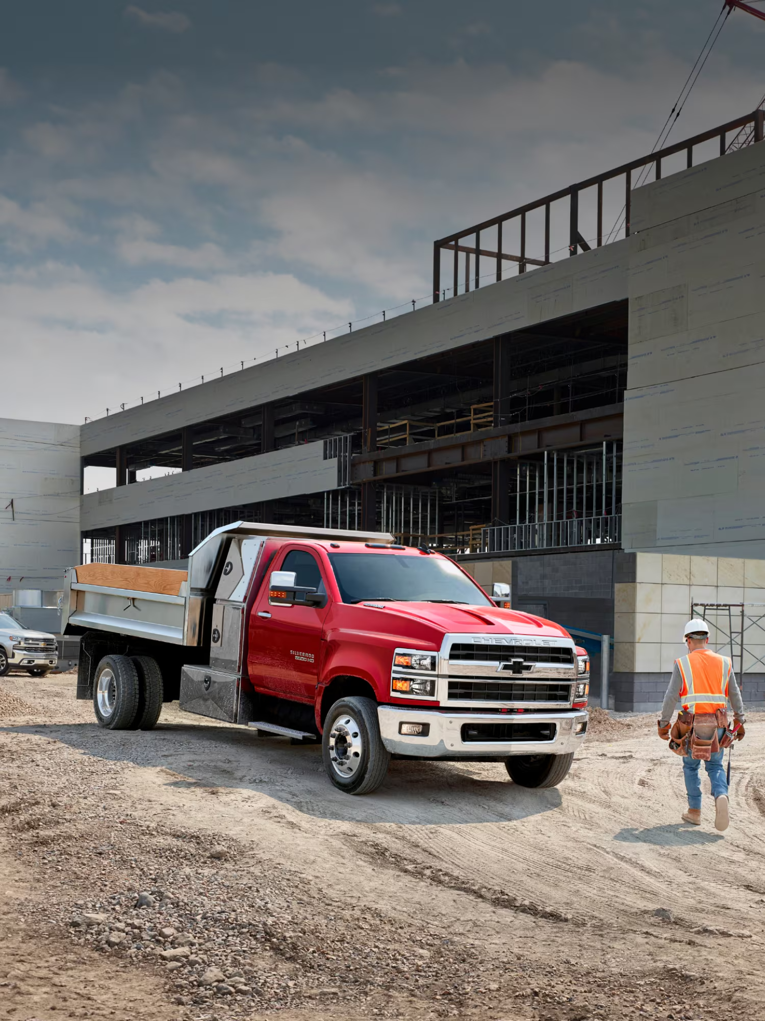 Red Chevy Silverado medium duty truck with a dump body at a commercial construction site