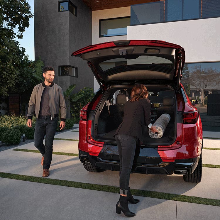 Couple loading gear into the rear cargo area of a red Chevy Blazer with the liftgate open