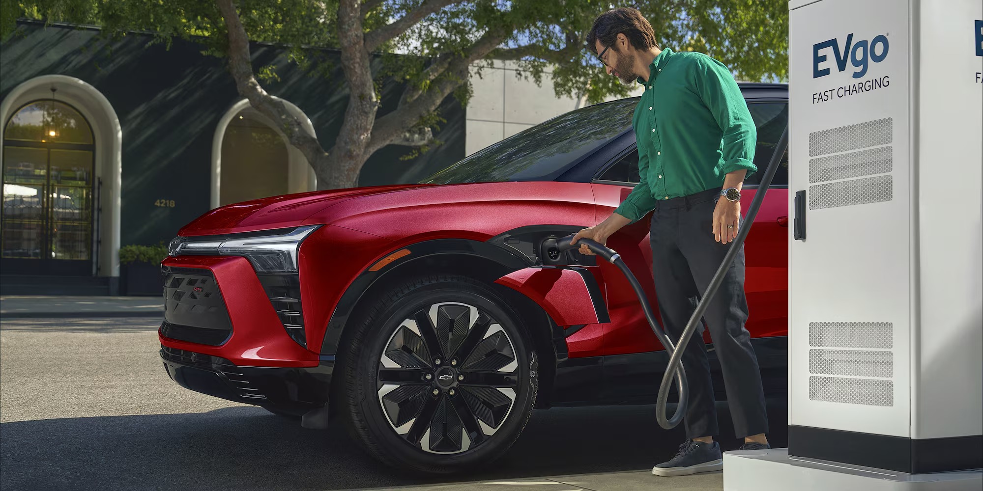 Driver plugging a red Chevy Blazer EV into a public DC fast charger