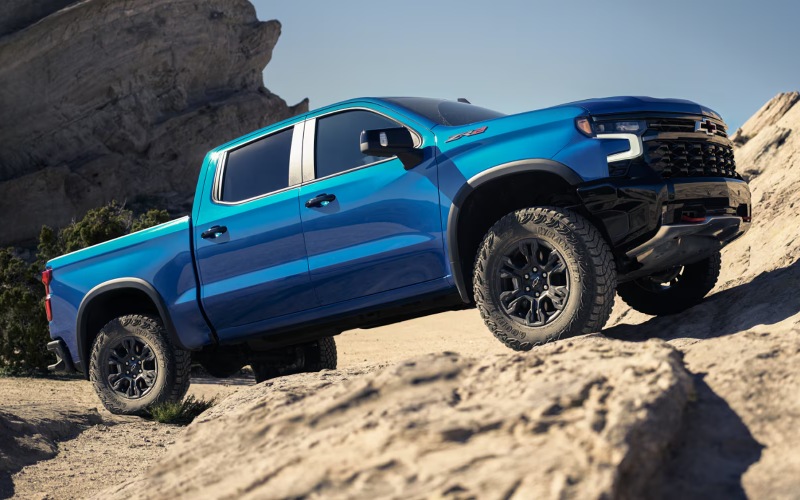 Blue Chevy Silverado ZR2 with off-road front bumper climbing a rocky slope