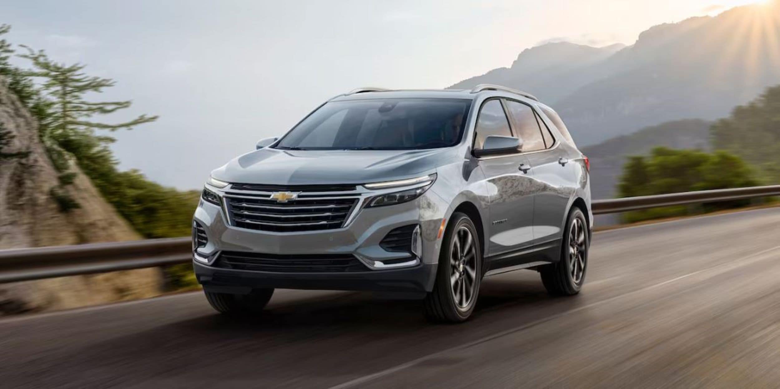 A silver Chevy Equinox driving down a windy road