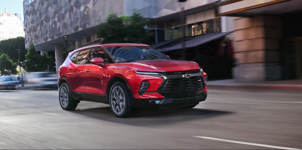 a-red-2023-chevy-blazer-driving-down-a-city-street.PNG