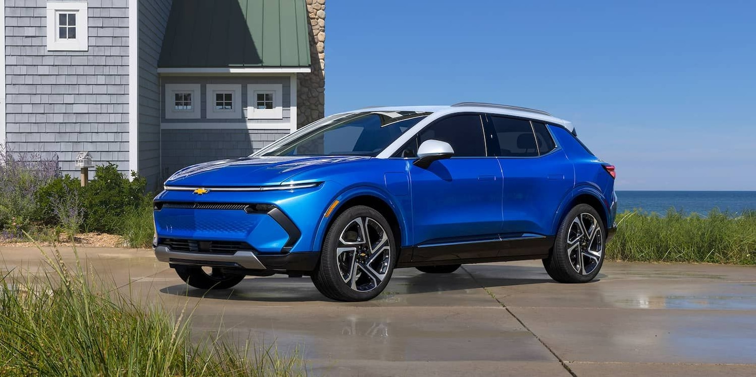 A cobalt blue 2023 Chevy Equinox sits parked in front of a shingle house on the coast.