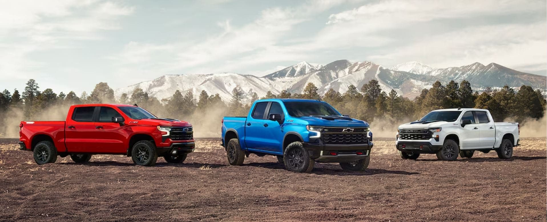 Three Silverado models displayed next to each other with mountains in the background.