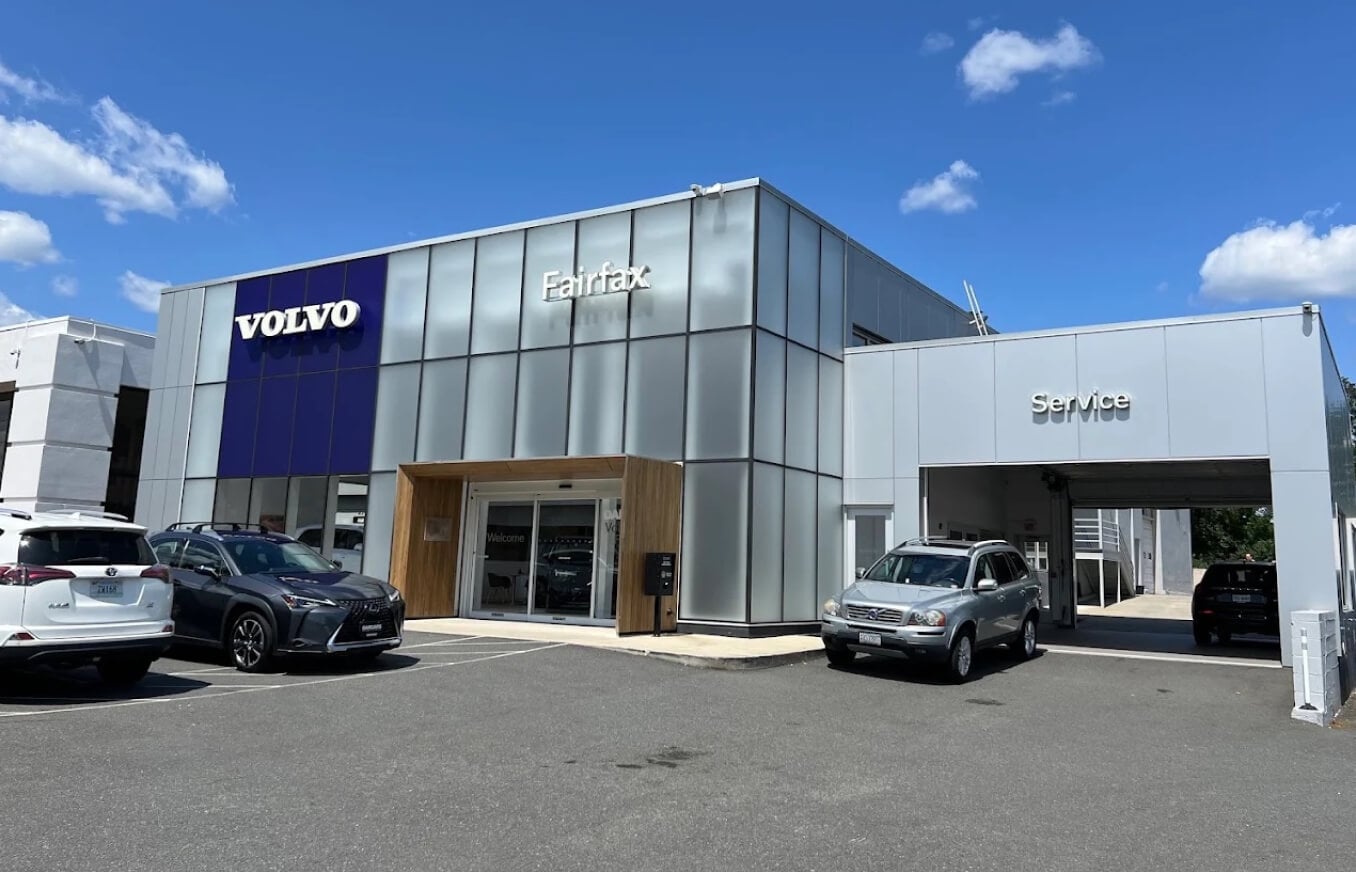 Exterior view of the DARCARS Volvo Cars Fairfax dealership building with cars parked under a blue sky.