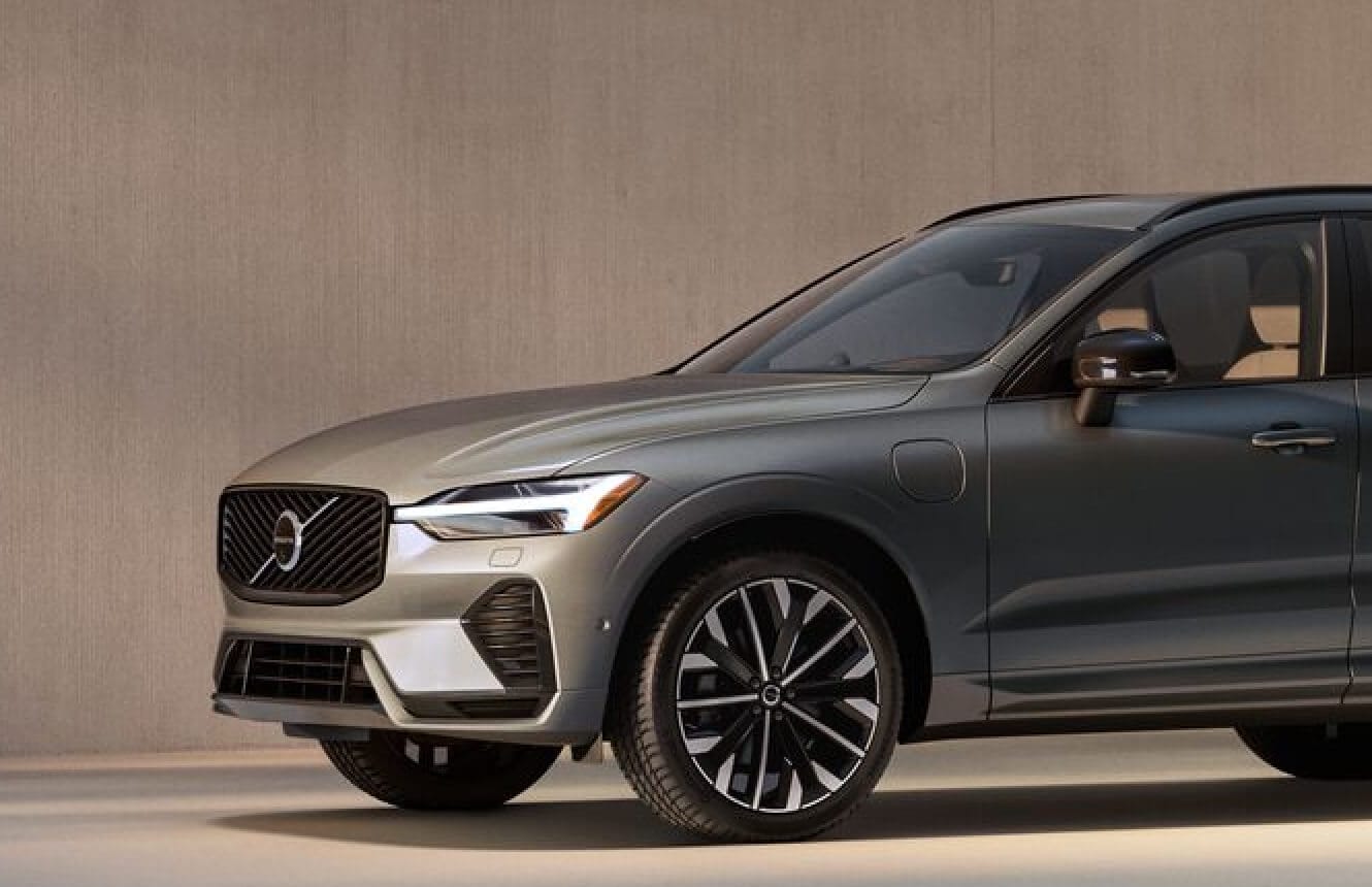Front three-quarter view of a grey 2026 Volvo XC60 PHEV parked against a concrete wall.