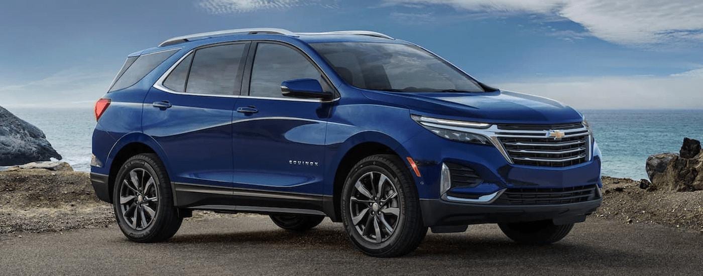 A blue used 2022 Chevy Equinox for sale is shown from the side near a body of water.