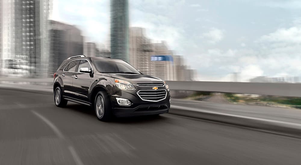 A black 2016 Chevy Equinox is shown driving on a city street.