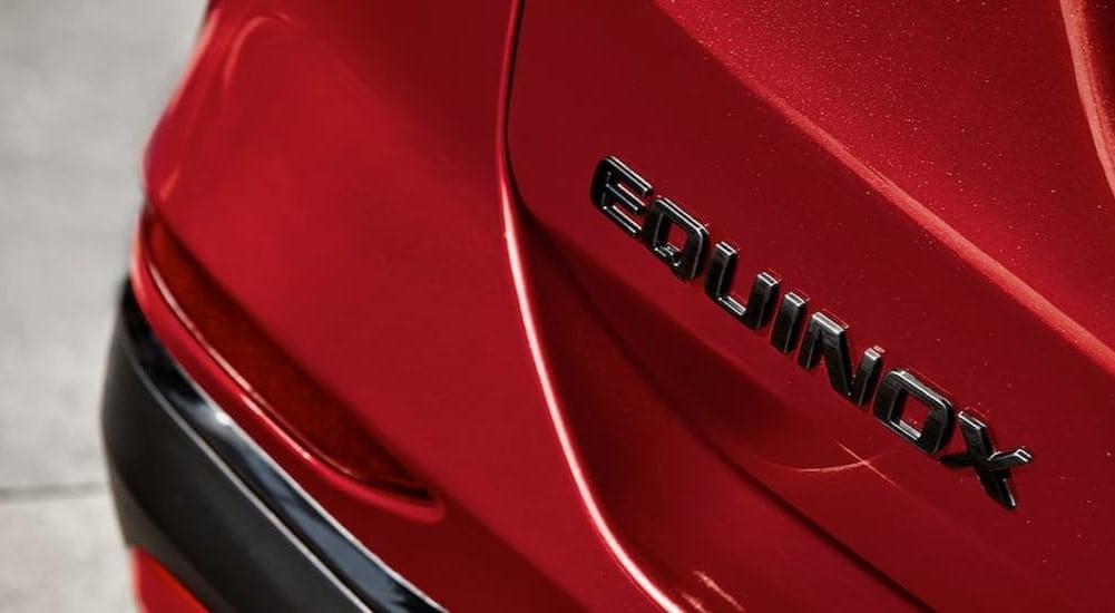 A close-up of the Equinox badge is shown on the hatch of a red 2024 Chevy Equinox.