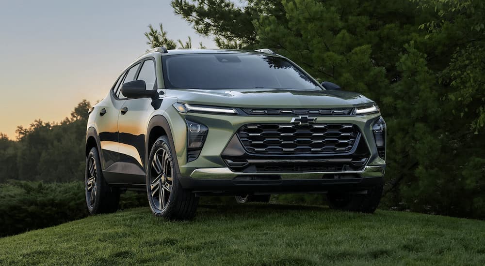 A green 2024 Chevy Trax for sale is shown parked on a grassy hill.