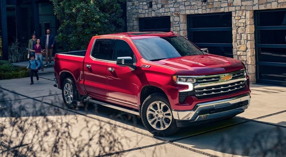 A red Chevy Silverado 1500 is shown parked near a family.
