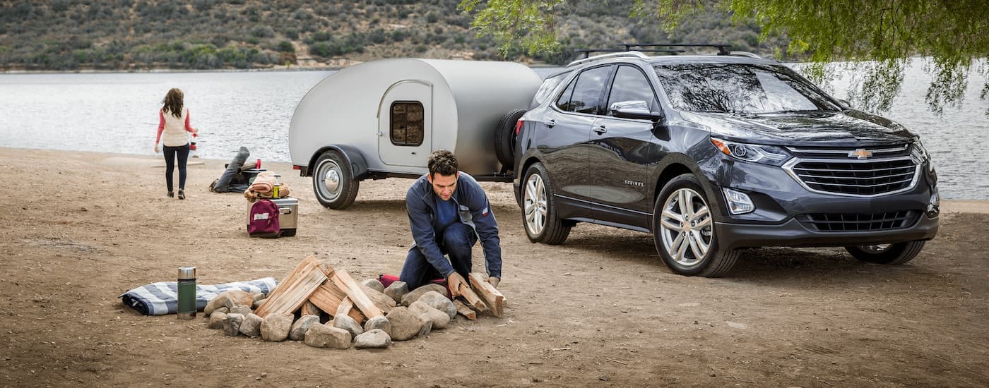 A grey 2020 Chevy Equinox is shown with a trailer at a campsite.