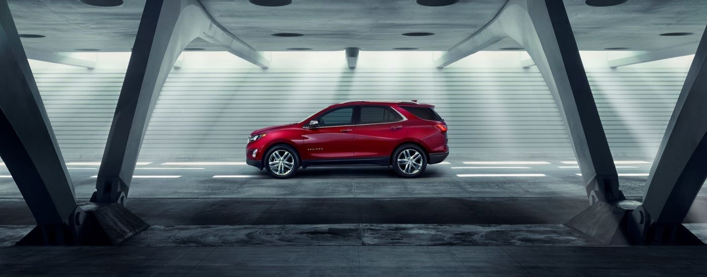 A red 2018 Chevy Equinox is shown from the side in parking garage.