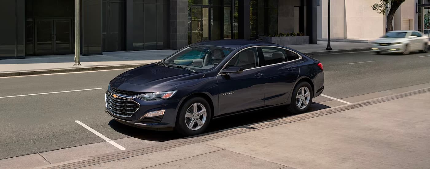 A dark blue 2023 Chevy Malibu is shown parked on a city street.