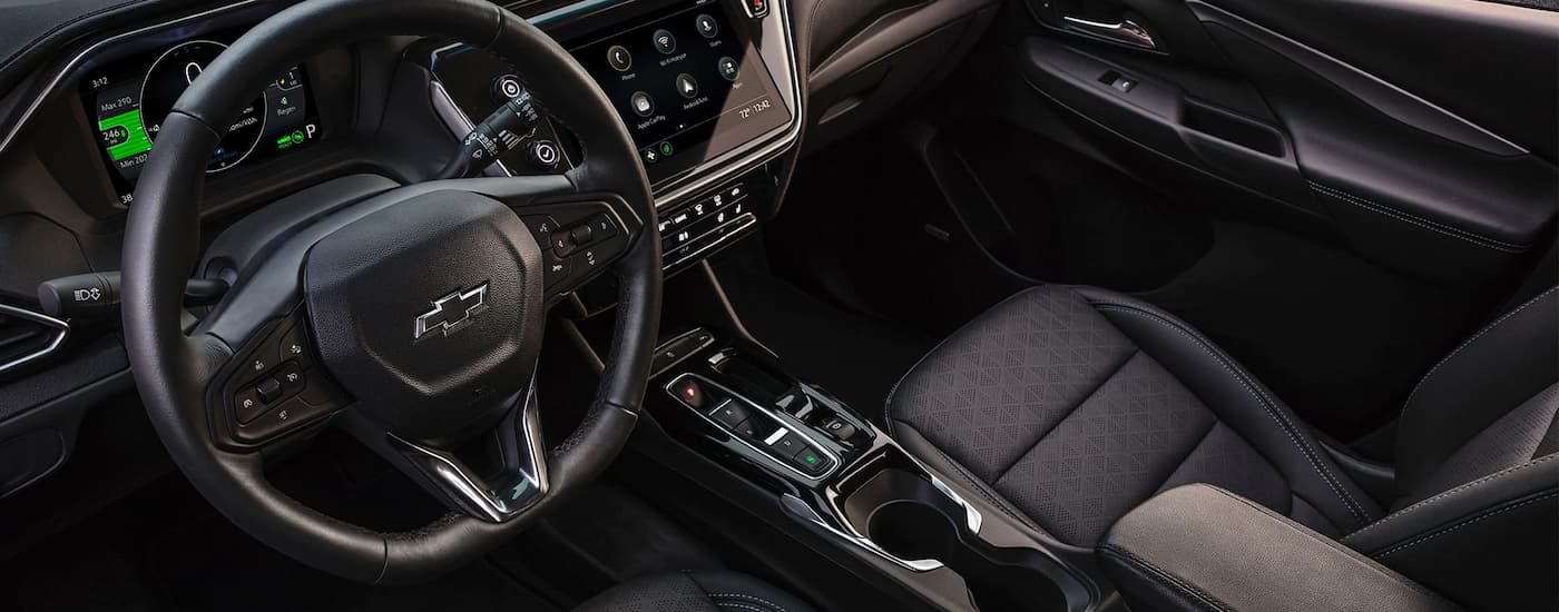 The black interior of a 2023 Chevy Bolt EV shows the steering wheel and center console.