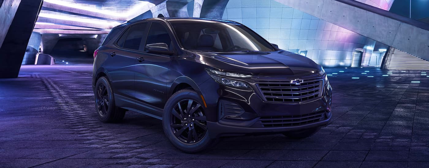 A black 2023 Chevy Equinox Midnight Edition is shown in front of a modern building.