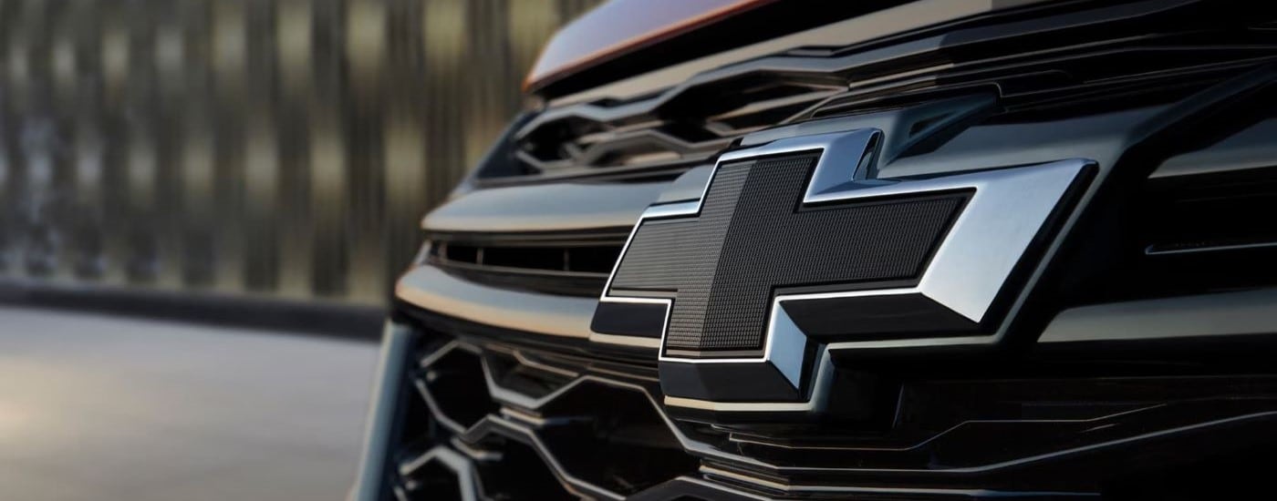 A close up shows the grille badge on a parked red 2023 Chevy Equinox RS near Columbus.
