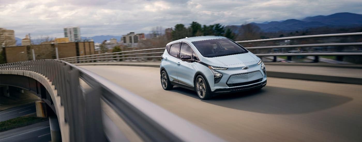 A blue 2023 Chevy Bolt EV is shown driving on an open highway.