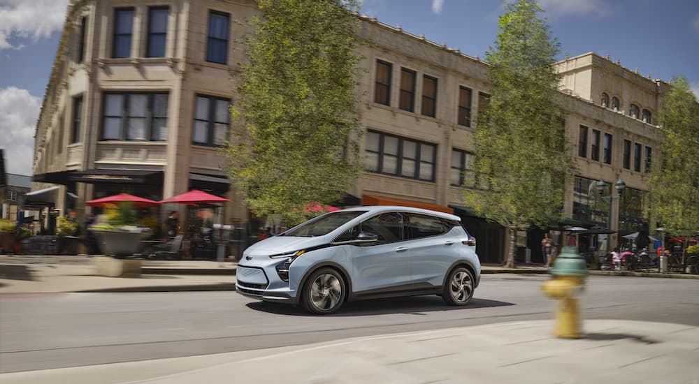 A blue 2022 Chevy Bolt is shown from the side on a city street.