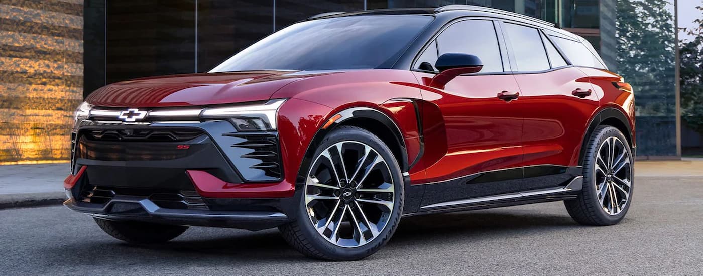 A red 2024 Chevy Blazer EV is shown from the side parked in front of a glass building.