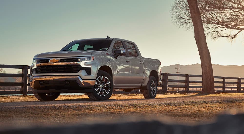 A silver 2023 Chevy Silverado 1500 Z71 is shown parked in front of a fence after leaving Chevrolet dealer.