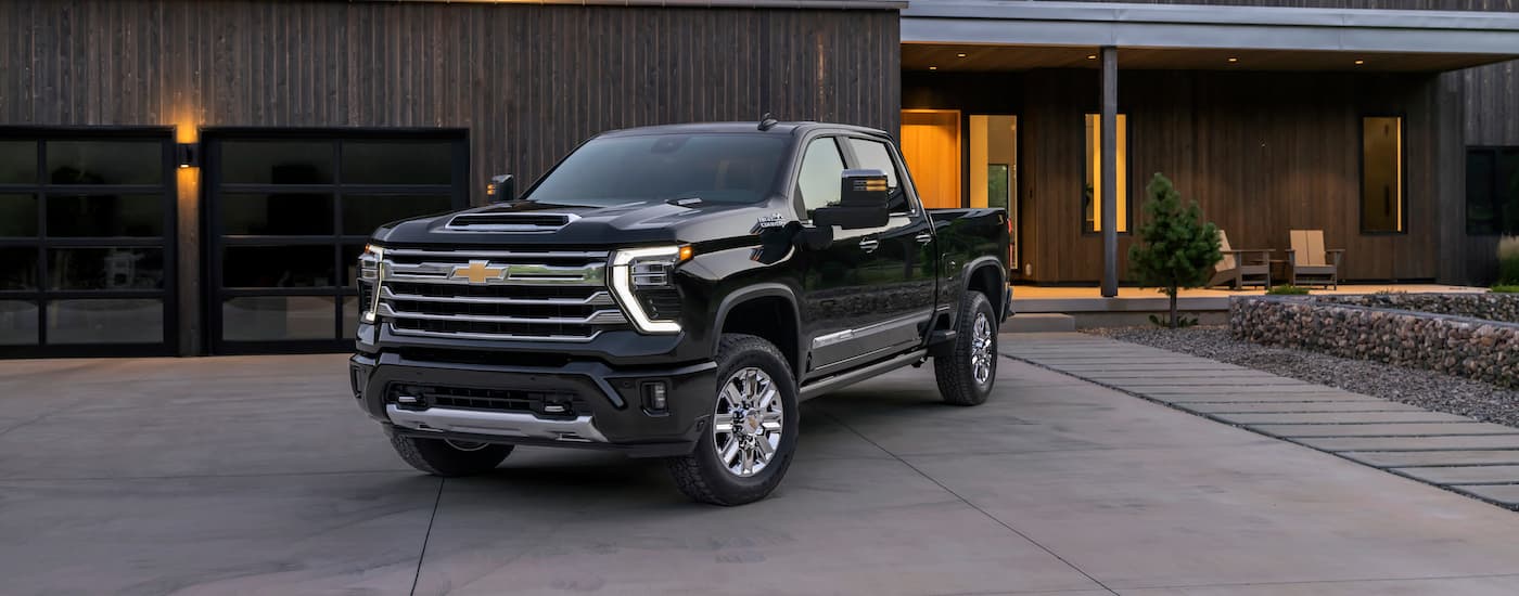 A black 2024 Chevy Silverado 2500HD High Country is shown parked on a driveway.