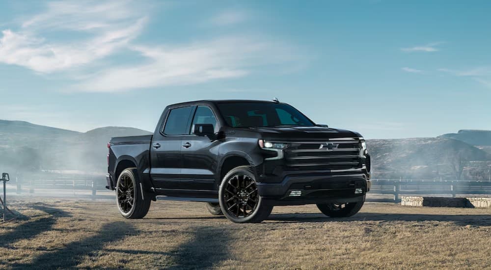 A black 2025 Chevy Silverado 1500 High Country is shown parked on a ranch.
