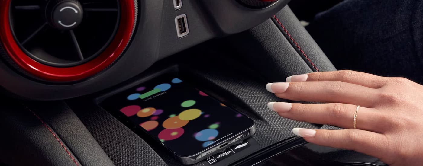 A close up of a hand reaching for a cell phone charging in a 2025 Chevy Blazer.
