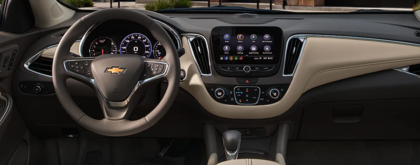 The steering wheel and dashboard in the brown interior of a 2024 Chevy Malibu.