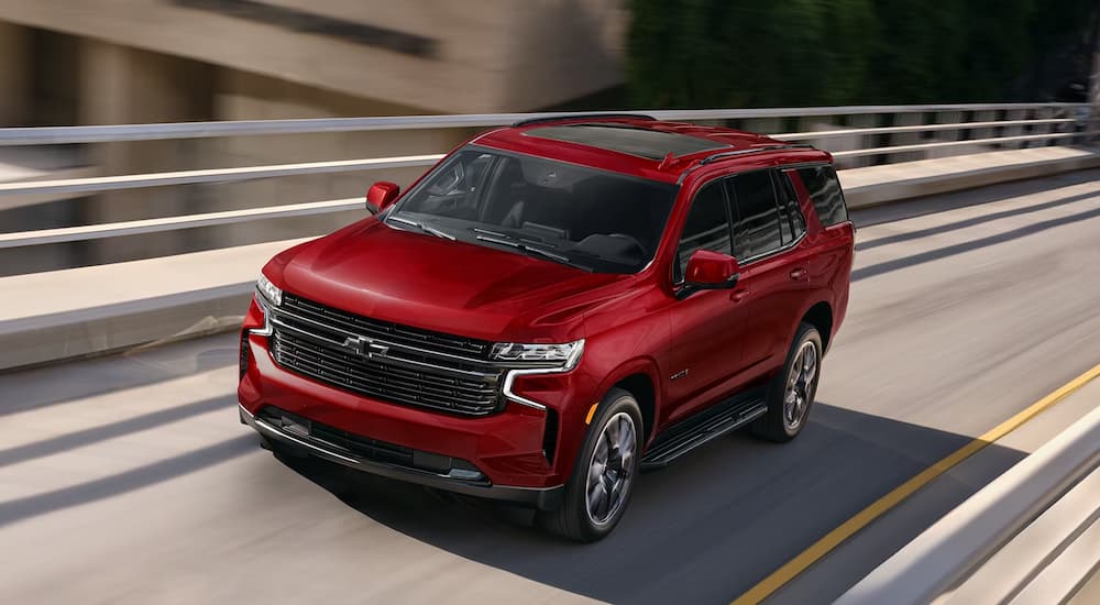 A red 2024 Chevy Tahoe RST is shown driving on a highway.