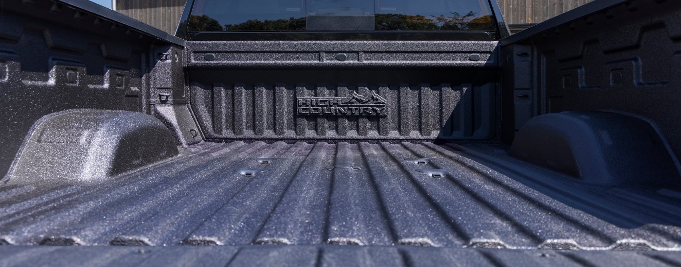 A close-up shows the bed of a black 2025 Chevy Silverado 2500 HD High Country.
